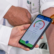Patch mit Sensor auf einem Männerarm, mit dem Smartphone werden die Daten ausgelesen