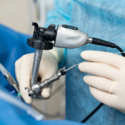 Hands in white latex gloves using special modern instruments while providing complex operation. Modern medicine. Cropped photo