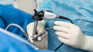 Hands in white latex gloves using special modern instruments while providing complex operation. Modern medicine. Cropped photo