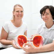 Dr. Ekaterina Sokolenko (rechts) und Anke Beckmann zeigen an einem Augenmodell, wo das PDS-Implantat im Auge sitzt. Die kleinen Fotos links oben verdeutlichen, dass das Implantat unter dem
Oberlid verschwindet, es ist normalerweise nicht sichtbar.